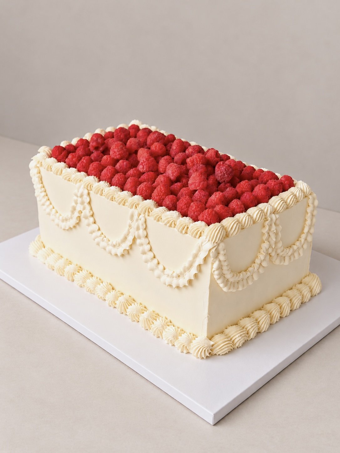 Rectangular cream cake topped with fresh raspberries