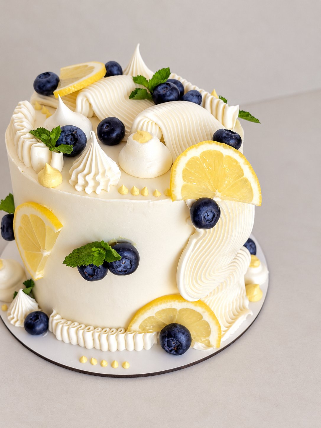Cream cake decorated with lemon, blueberries and meringues
