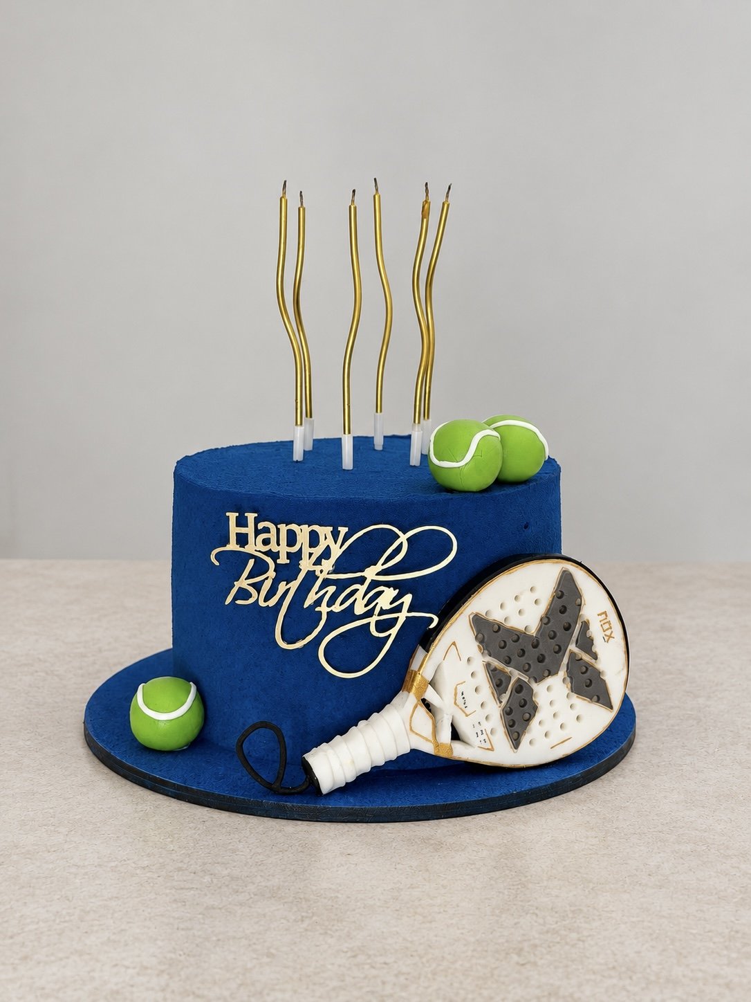 Blue birthday cake with a padel racket and green balls